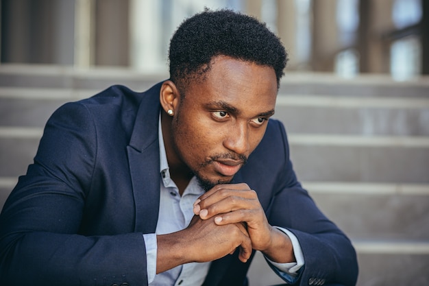 Photo african american businessman in business suit frustrated got bad news from work, fired depressed sitting on stairs, close-up portrait photo