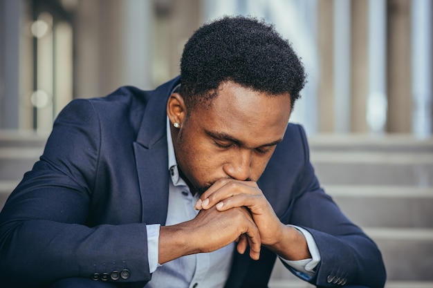 Photo african american businessman in business suit frustrated got bad news from work, fired depressed sitting on stairs, close-up portrait photo