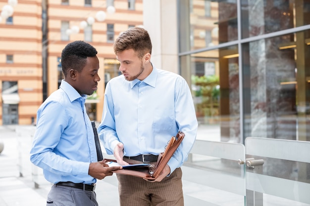 African American businessman and a Caucasian businessman discussing and looking at the documents on city