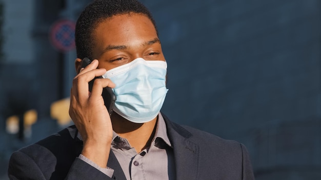 African american businessman ethnic man male guy in medical face mask talking mobile phone answer