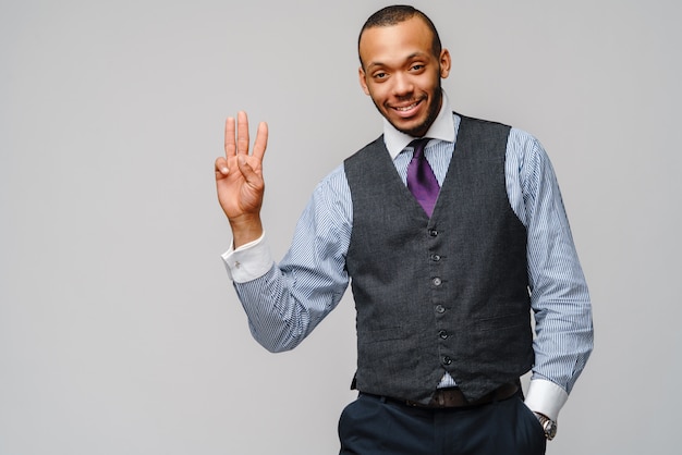 African-American businessman showing three fingers over grey wall