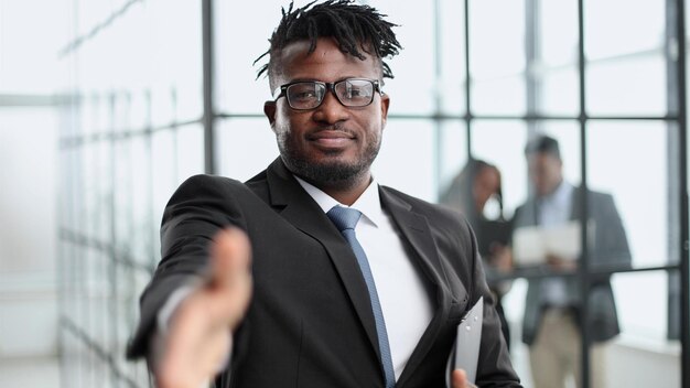 African american businessman in suit and glasses reaching out to shake hands