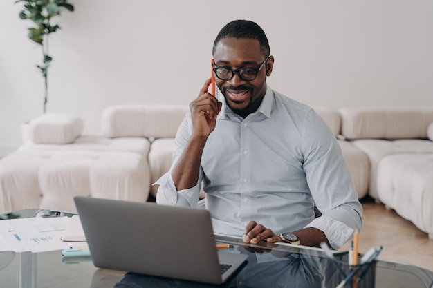 African american businessman talking on phone at laptop advises client sells conducts negotiations