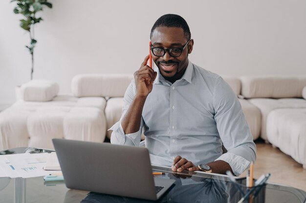 African american businessman talking on phone at laptop advises\
client sells conducts negotiations