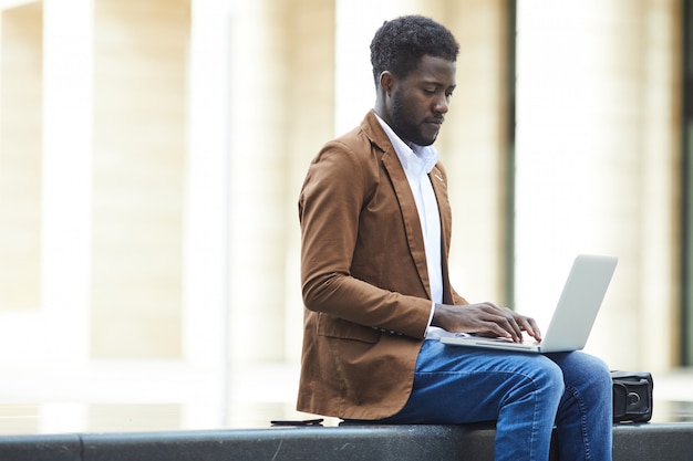 Афро-американский бизнесмен, используя ноутбук в городе