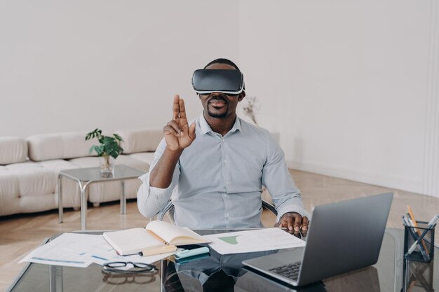 African american businessman using virtual reality glasses working at laptop Hightech ebusiness