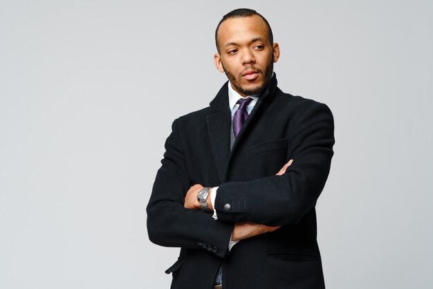  of a african-american businessman wearing coat over light grey wall.