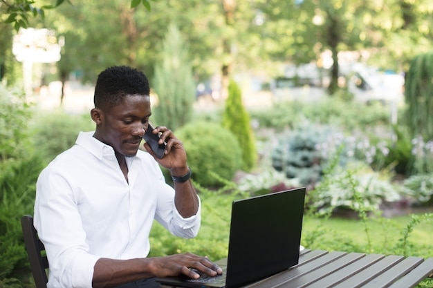 Uomo d'affari afroamericano che lavora al computer portatile in un bar