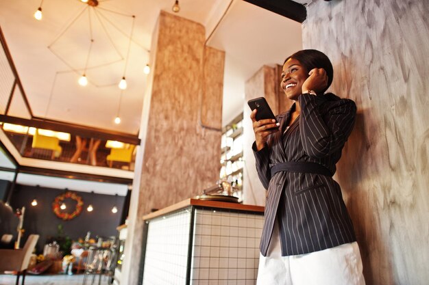 African american businesswoman in cafe with mobile phone Black girl having rest