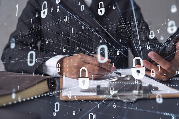 african american businesswoman in formal wear signing the contract to prevent probability of risks in cyber security checking the phone padlock hologram icons over the working desk