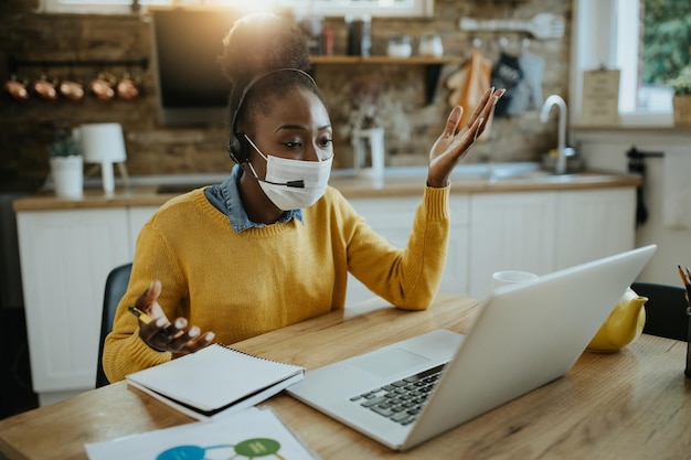 Donna d'affari afroamericana che effettua una videochiamata sul laptop mentre lavora a casa a causa della pandemia di coronavirus
