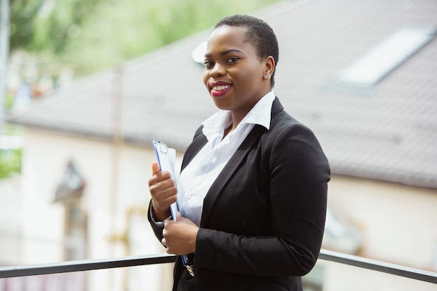 African-american businesswoman in office attire smiling, looks confident and happy, successful