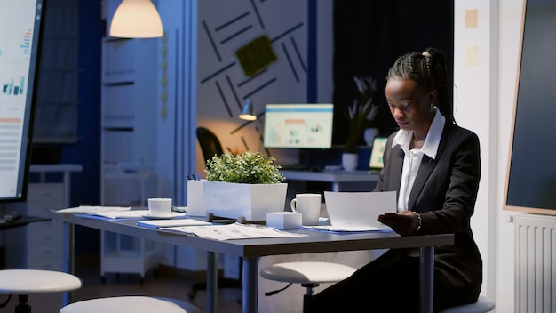 african american businesswoman sitting at conference table drinking coffee