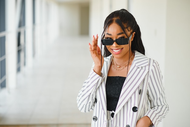 African-American businesswoman speaking by smartphone in office hall, copy space