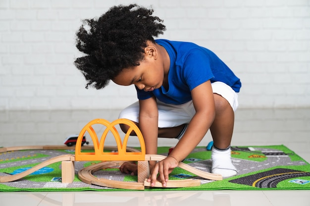 Photo african american child playing with his car toys at home