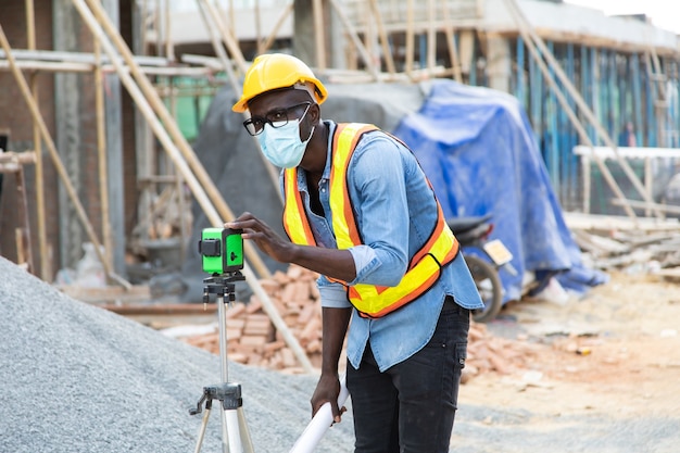 African American construction worker on building site. wearing surgical face mask during coronavirus covid and flu outbreak