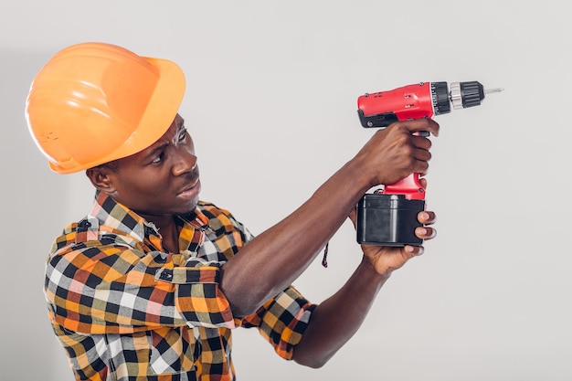 African American construction worker in helmet uses electric screwdriver