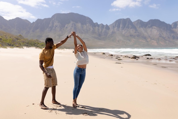 African american couple having fun dancing on a beach by the sea. healthy lifestyle, leisure in nature.