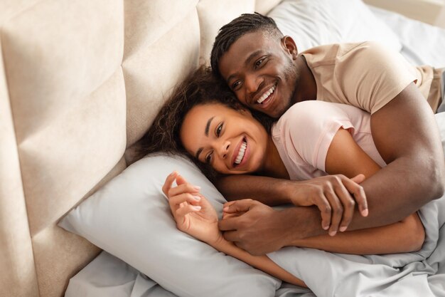 Photo african american couple resting in bedroom together hugging and smiling