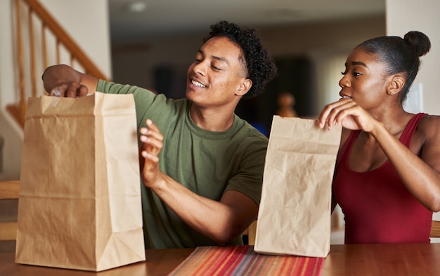 食品配達を見ているテーブルに座っているアフリカ系アメリカ人のカップル