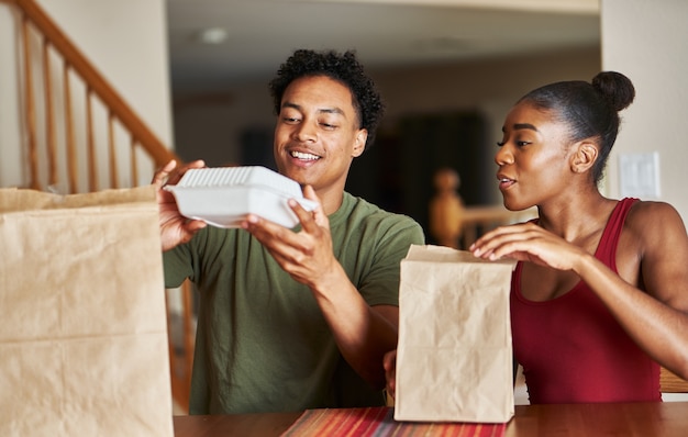 食品配達を見ているテーブルに座っているアフリカ系アメリカ人のカップル