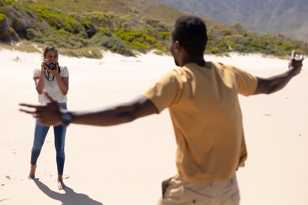 Афро-американская пара фотографирует с камерой на пляже у моря. здоровый образ жизни, отдых на природе.