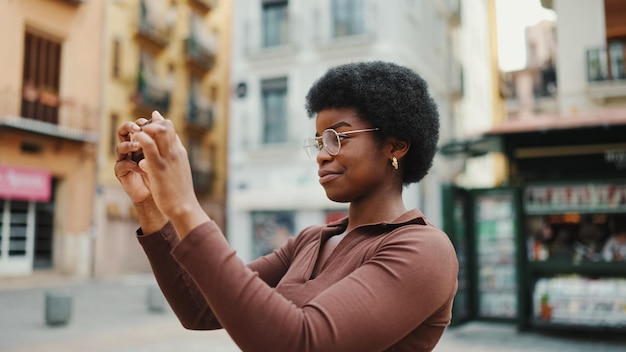 散歩中に写真を撮る眼鏡のアフリカ系アメリカ人の巻き毛の女の子