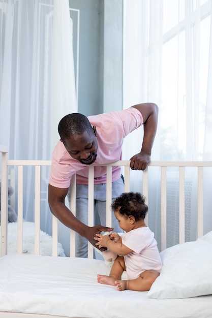 African-American dad puts baby son to bed at home