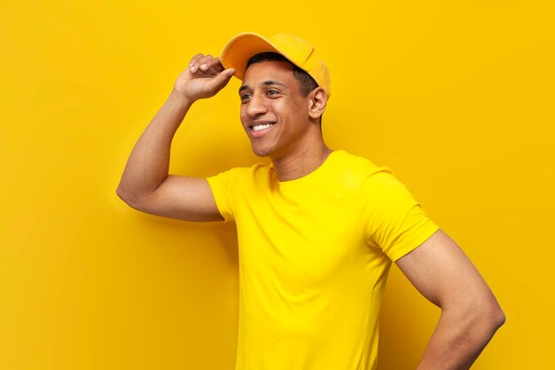 African american delivery man in yellow uniform stands on yellow background service worker