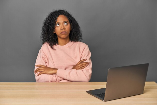 Photo african american at desk with laptop tired of a repetitive task