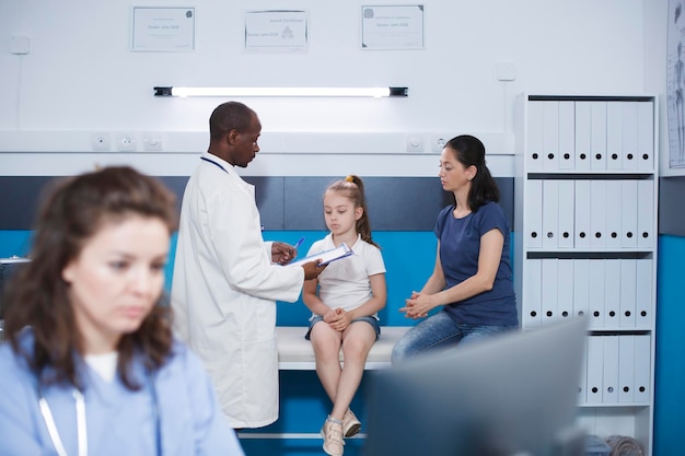 Photo african american doctor examines a young patient explaining the condition while wearing a lab coat effective communication promotes health in this calm and professional setting focus on background