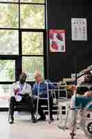 Photo african american doctor holding clipboard explaining medical expertise to senior patient with wallking frame during consultation in hospital waiting area. medicine service and concept