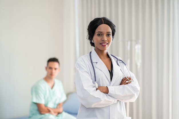 The african american doctor is checking the symptoms by checking the patient's heart on the patient's bed. And provide consultation regarding treatment to patients sitting