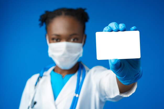 African american doctor woman hold blank empty business card in blue studio