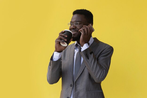  African American drinks coffee and talks on  phone, on a yellow background