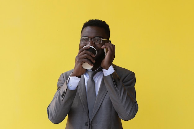 African American drinkt koffie en praat over de telefoon, op een gele achtergrond