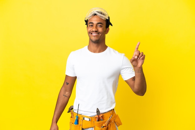 African American electrician man over isolated yellow wall showing and lifting a finger in sign of the best