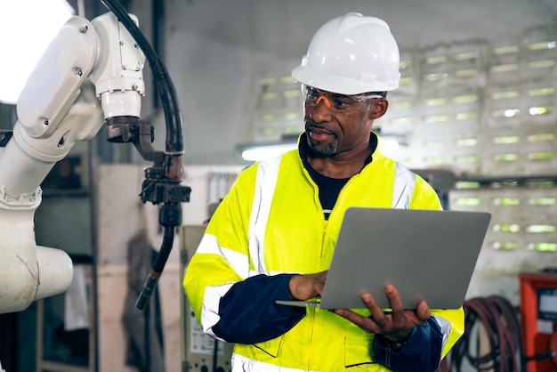 African american factory worker working with adept robotic arm