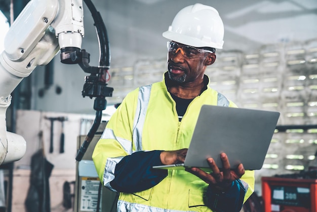 African American factory worker working with adept robotic arm