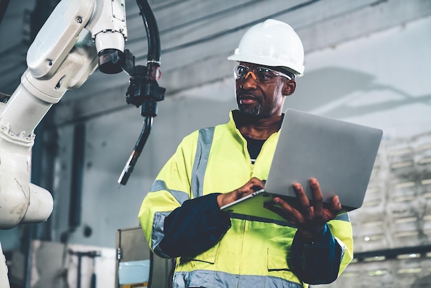 African American factory worker working with adept robotic arm