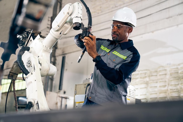 능숙한 로봇 팔로 일하는 아프리카계 미국인 공장 노동자