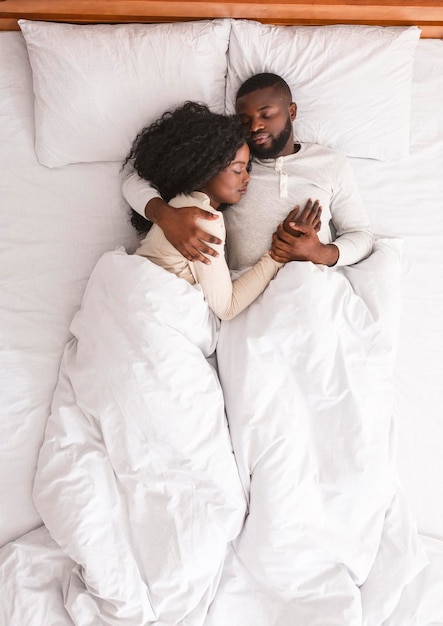 横臥とベッドで抱きしめる、一緒に寝ているアフリカ系アメリカ人の家族のカップル、上面図