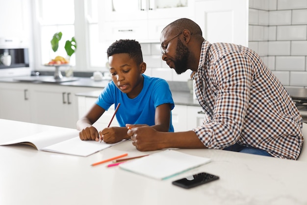 Foto padre e figlio afroamericani in cucina, facendo i compiti insieme