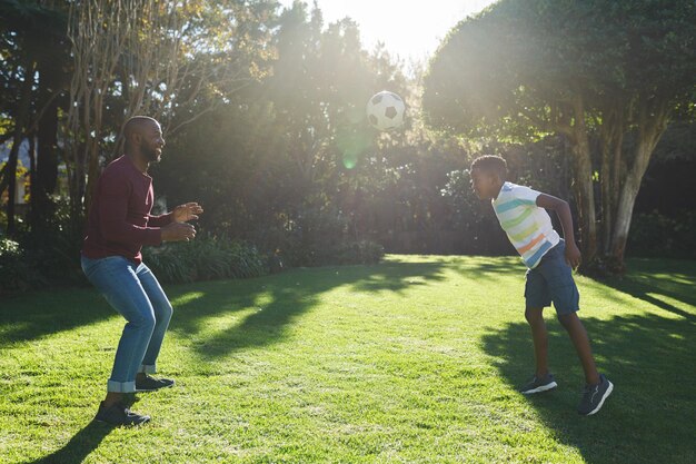 写真 アフリカ系アメリカ人の父親と息子が庭でサッカーを楽しんでいます