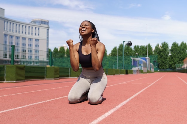 African american female athlete feels happy after running long\
distance on track at sports ground