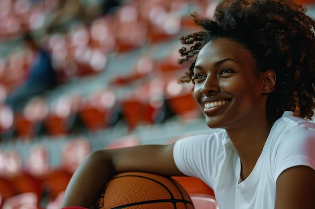 Foto una giocatrice di basket afroamericana seduta sullo stadio sta sorridente donna con una palla da basket che incarna il concetto di passione per il gioco sportivo e l'addestramento fisico