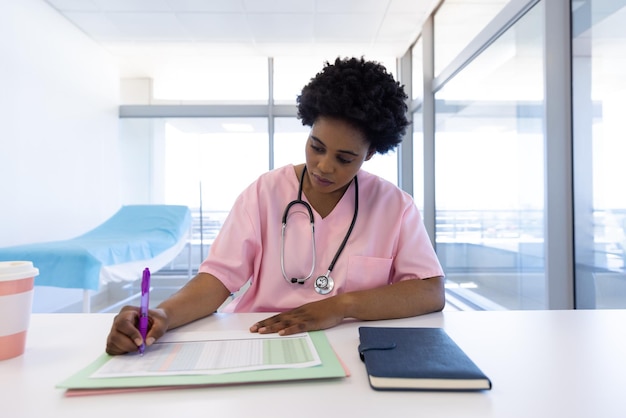 Photo african american female doctor writing in sunny hospital office