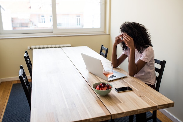 Free lance femminili afroamericane che utilizzano computer portatile nella cucina