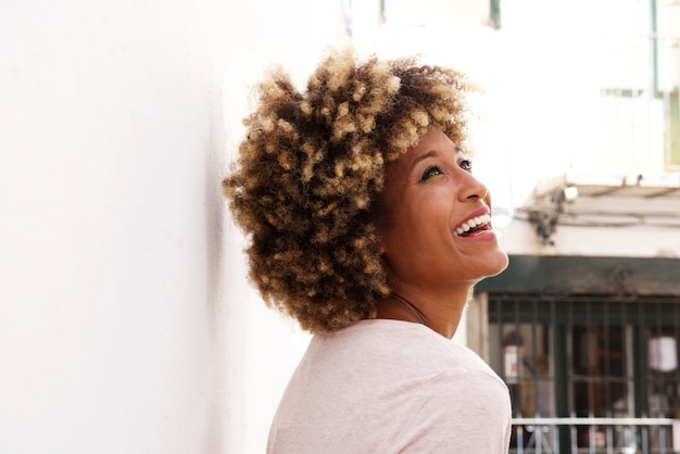 African american female standing by a white wall and laughing