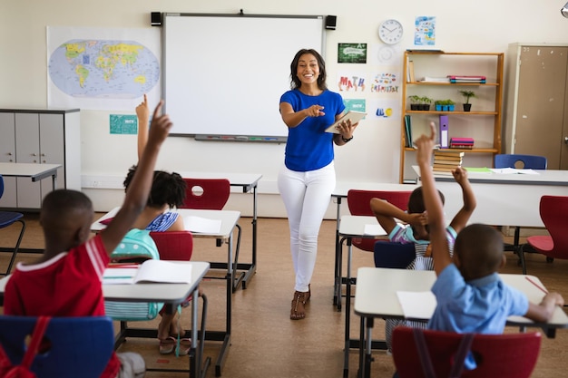 小学校のクラスでデジタル タブレットを教えるアフリカ系アメリカ人の女性教師